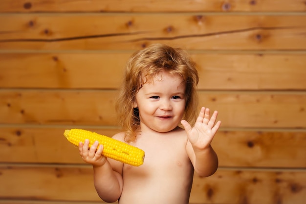 Funny small boy child eating yellow corn