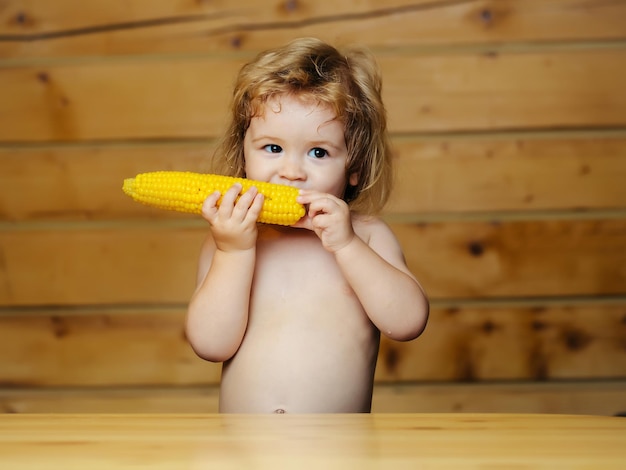 Funny small boy child eating yellow corn