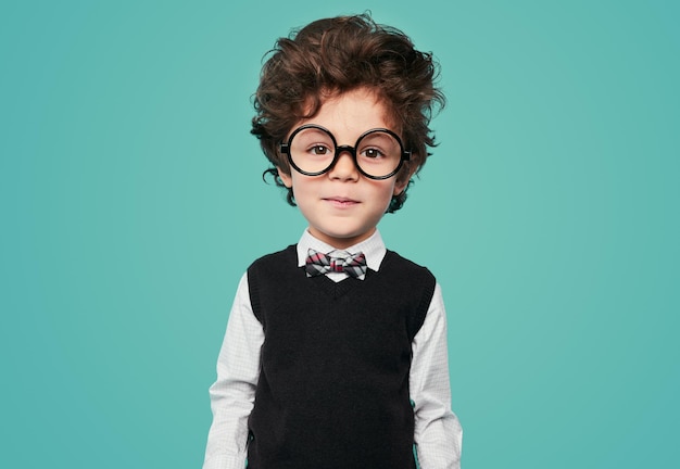 Funny smart kid in round eyeglasses smiling in studio