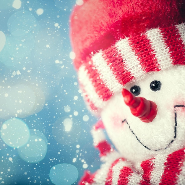 Funny snowman portrait against snowfall abstract christmas backgrounds