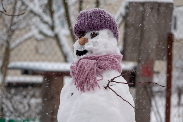 Funny snowman in stylish black hat on snowy field.