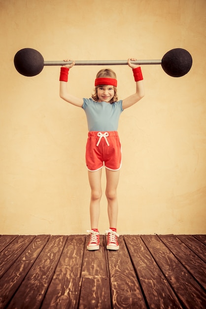 Funny strong child with barbell. Girl power and feminism concept. Sport fitness success winner kid