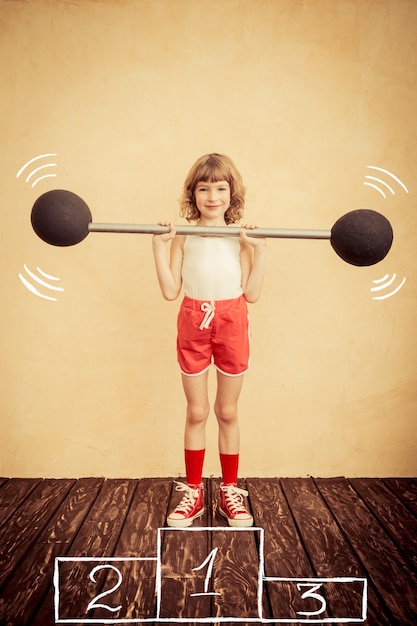 Funny strong child with barbell. Girl power and feminism concept. Sport fitness success winner kid