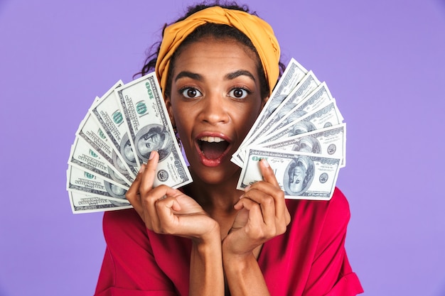 Funny surprised african woman in dress holding money
