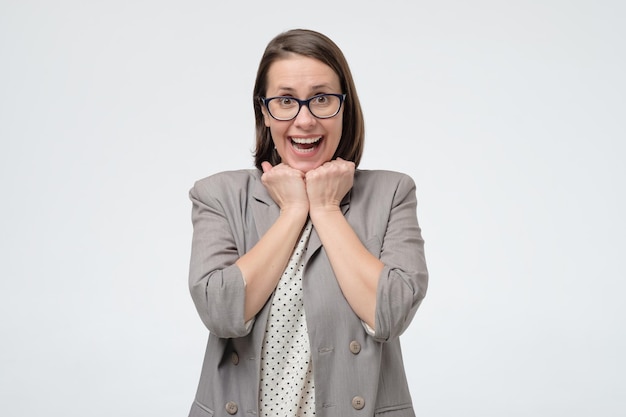 Funny surprised business woman in suit looking at camera feel amazed excited