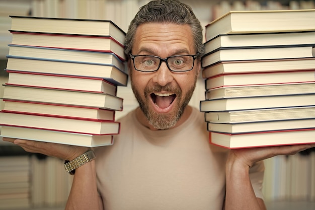 Photo funny teacher hold many books crazy teacher with books excited teacher in school book library