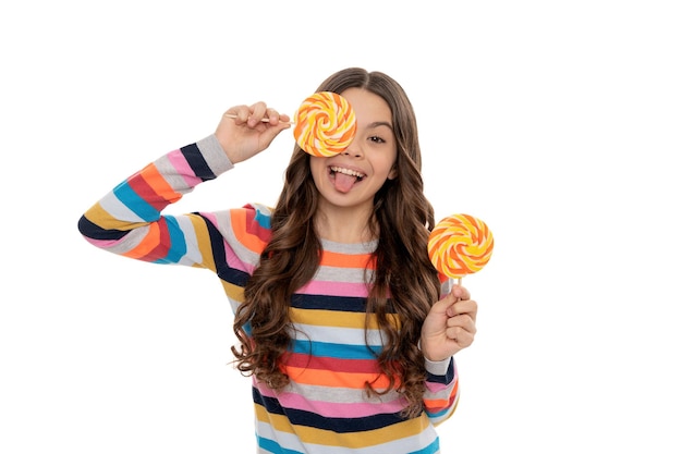 Ragazza teenager divertente in maglione colorato con caramelle lecca-lecca su bastone isolato su sfondo bianco, negozio di caramello.