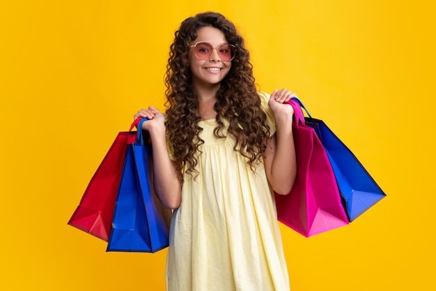 Funny teen girl hold shopping bag enjoying sale isolated on yellow portrait of teenager schoolgirl is ready to go shopping summer shopping sale