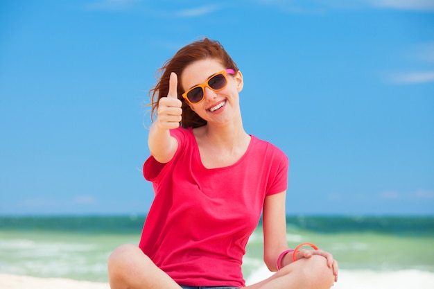 Funny teen girl sitting on the sand at the beach.