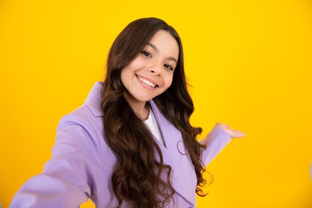 Funny teenager girl making selfie posing on yellow background happy teenager positive and smiling emotions of teen girl