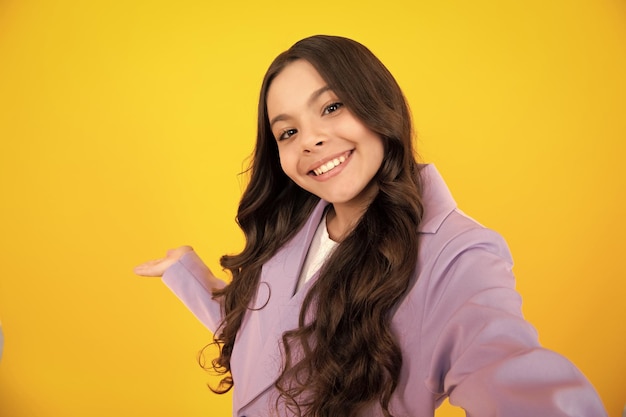 Funny teenager girl making selfie posing on yellow background Happy teenager positive and smiling emotions of teen girl