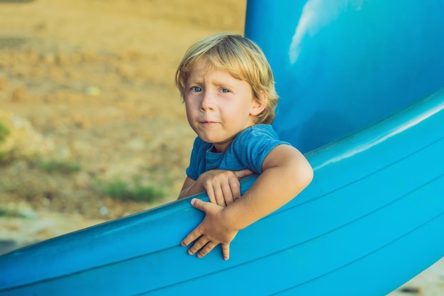 Funny toddler boy having fun on slide on playground