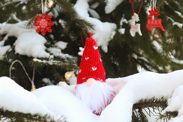 面白いおもちゃのノームは、雪に覆われた枝に座っていますお祝いのクリスマスや新年の背景