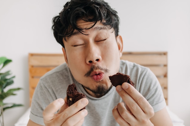 Funny very delicious happy face of man eat a chocolate cookie