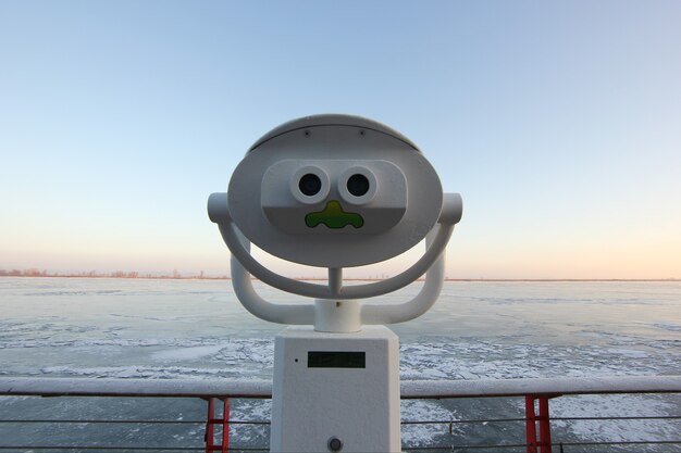 funny view of the panoramic binoculars on the background of the frozen river