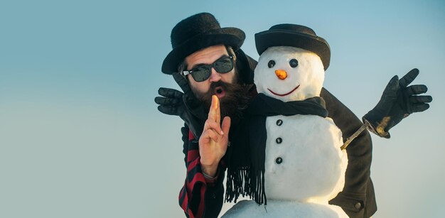 Photo funny winter snowman in hat play with snowman outdoor man with snowman on winter outdoor background