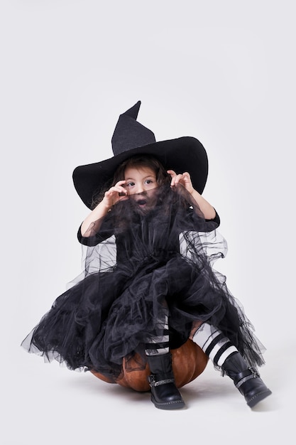 호박에 앉아 모자에 재미있는 마녀 소녀.