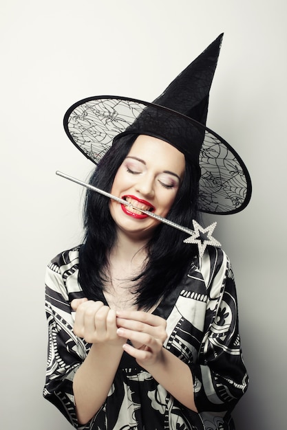 Смешная ведьма Молодая счастливая женщина с canival шляпой.