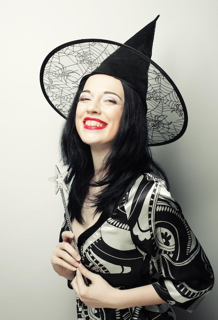 面白い魔女キャニバル帽子を持つ若い幸せな女性