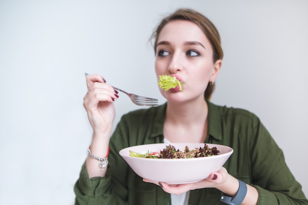 Foto donna divertente che mangia i verdi di insalata. ragazza carina con piatto di insalata nelle loro mani. mangiare sano e cibo sano.