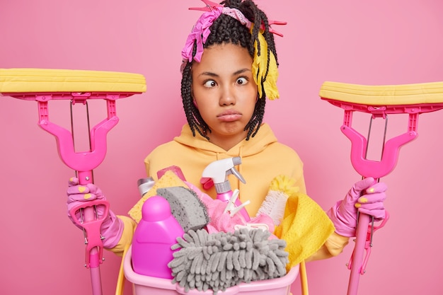 Funny woman foolishes around while doing housework makes grimace pouts lips crosses eyes