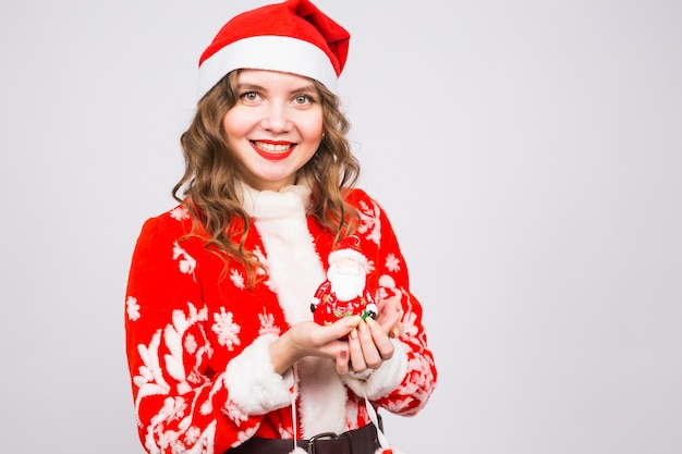 Funny woman in Santa costume holding a Santa figurine