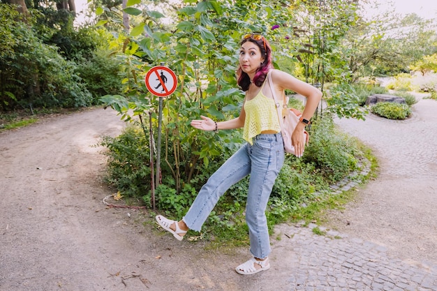 Photo funny woman violating prohibition sign in a city park fun and humor concept