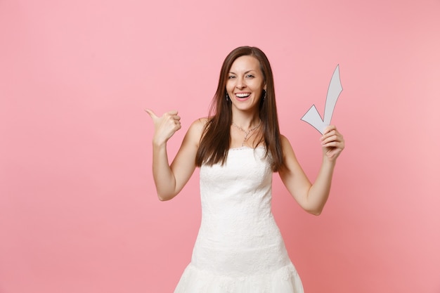 Funny woman in white dress pointing thumb aside holding check mark