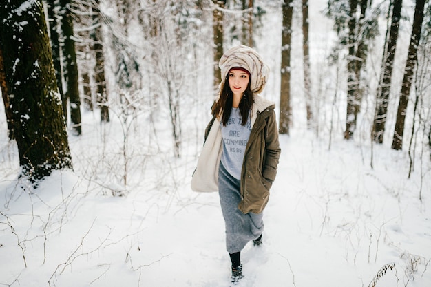 Funny young attractive girl with a turban from the scarf walking in the snow forest