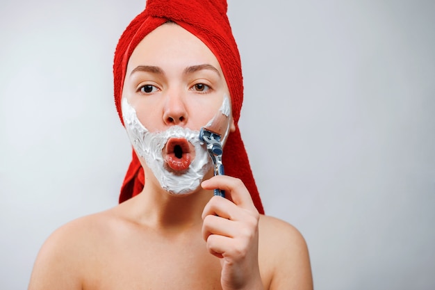 funny young beautiful woman shaves her beard with a razor