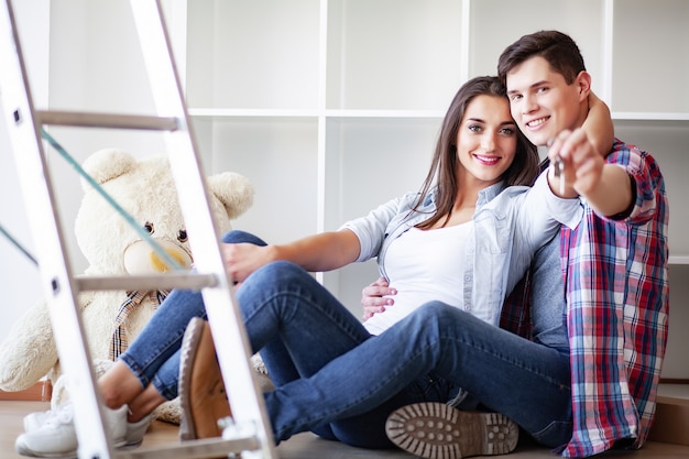 Funny young couple enjoy and celebrating moving to new home. Happy couple at empty room of new home