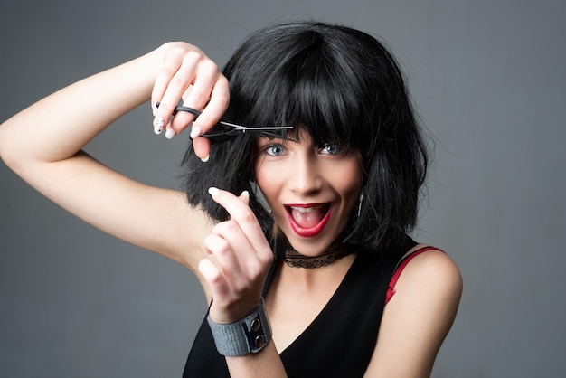 Funny young girl with short brunette hair and hairdressers scissors attractive young woman is cuttin
