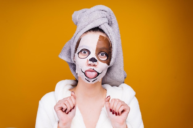 Photo funny young girl with a towel on her head showing tongue on face a mask with mask of a dog