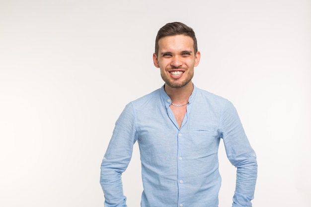 Funny young handsome man smiling on white wall with copy space