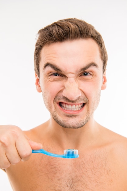 Funny young man holding toothbrush