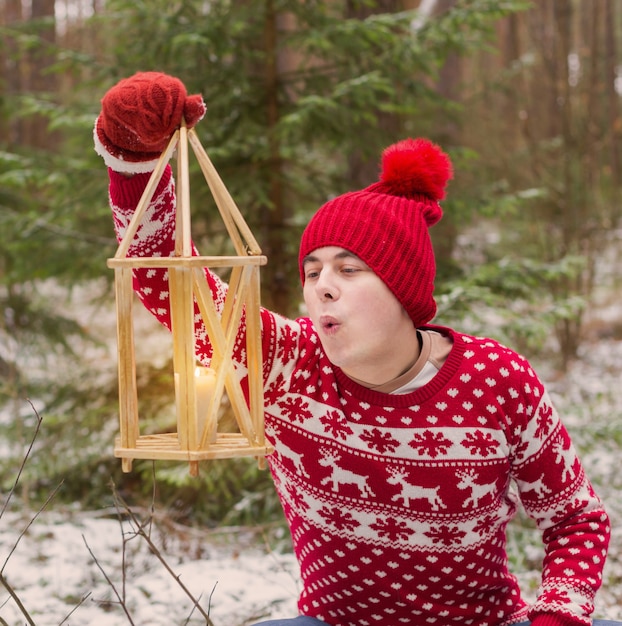 Забавный молодой человек в красной шляпе в зимнем лесу