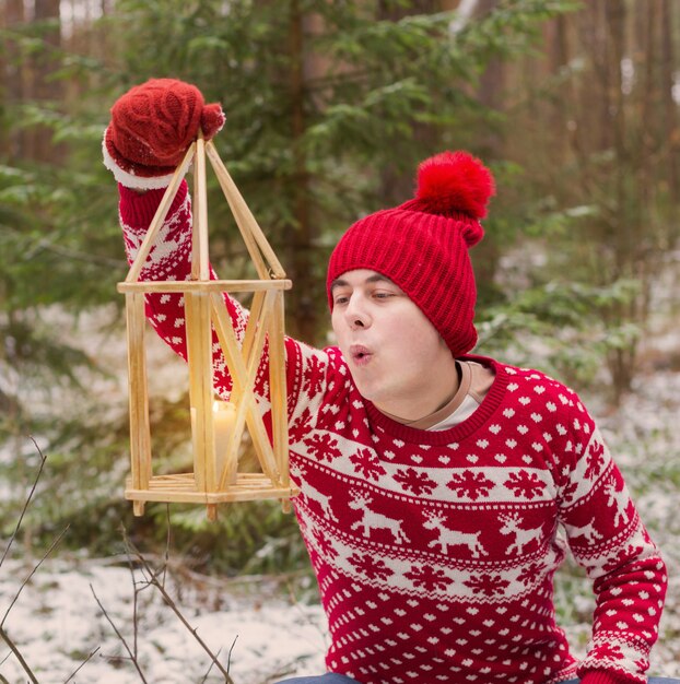 Funny young man in red hat in winter forest