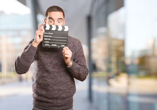 Funny young man using a clapperboard