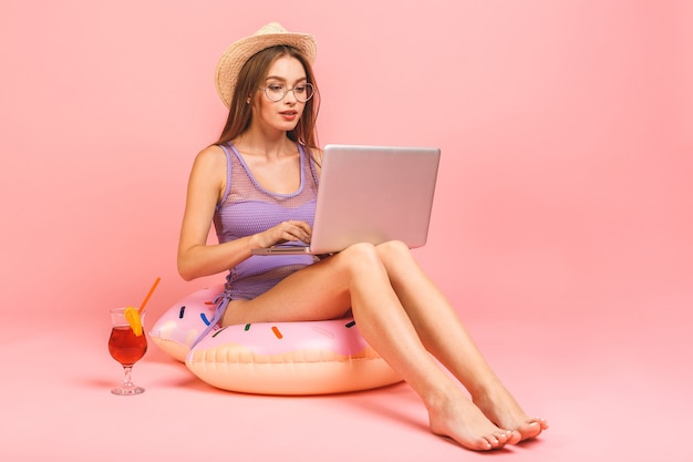 Funny young woman in swimsuit working on laptop