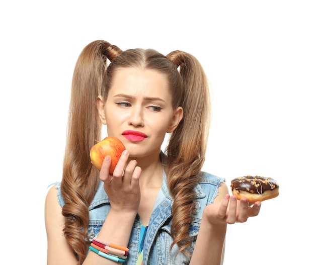 Смешная молодая женщина с яблоком и пончиком на белом фоне