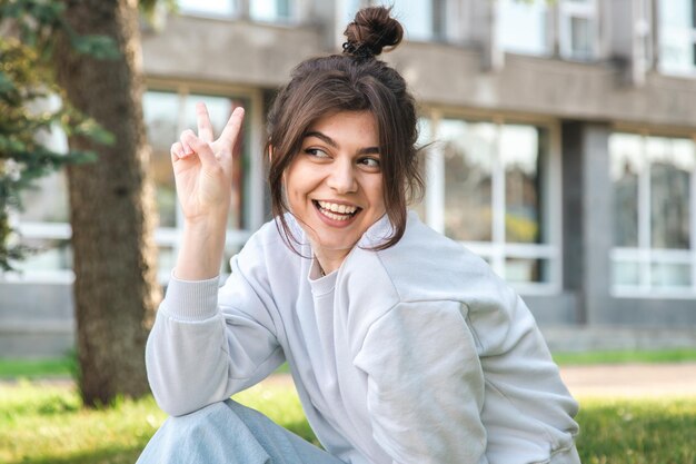 Funny young woman with a bun on her head in a city park