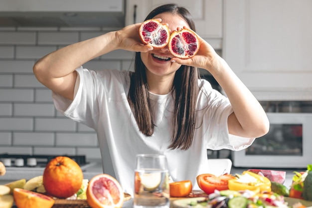 Funny young woman with orange halves in the kitchen