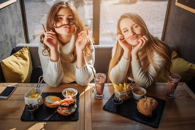 Le giovani donne divertenti osservano sulla macchina fotografica e posano