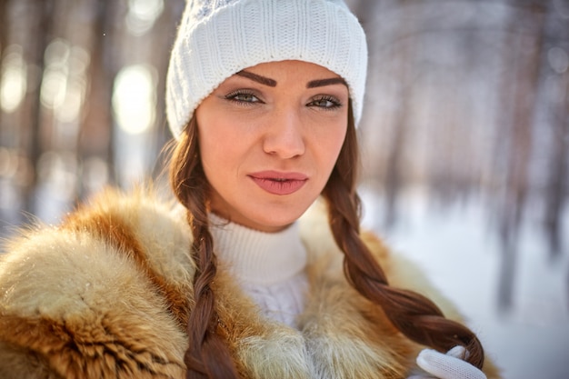 Gilet di pelliccia su una bellissima giovane donna caucasica in una foresta di sole invernale