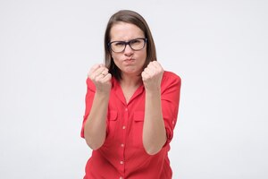 Furious and angry woman in glasses holding fist up