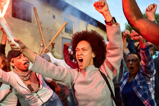 Furious black woman and group of activists shouting while\
protesting for human rights on the streets