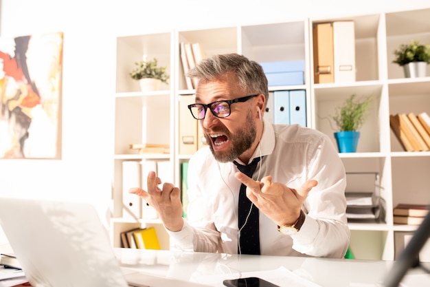 Photo furious businessman showing fucks to laptop