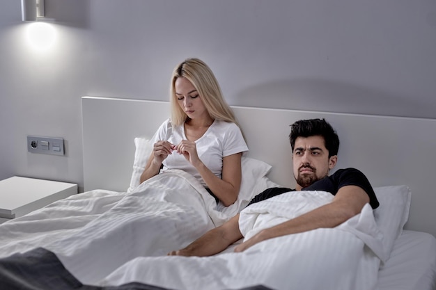 Фото Разъяренная кавказская женщина и мужчина во время ссоры дома сидят на кровати и не разговаривают