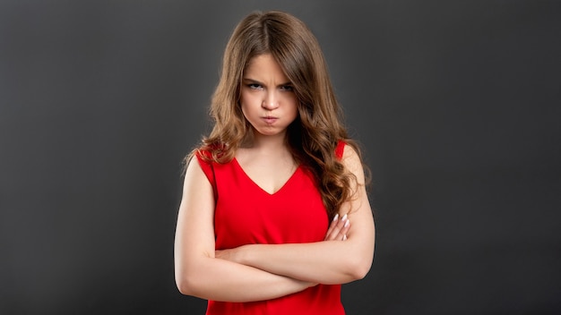 Furious woman portrait. Irritation jealousy. Displeased lady in red with folded arms grimacing 