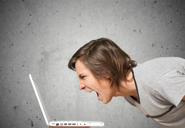 Furious young man screaming on laptop